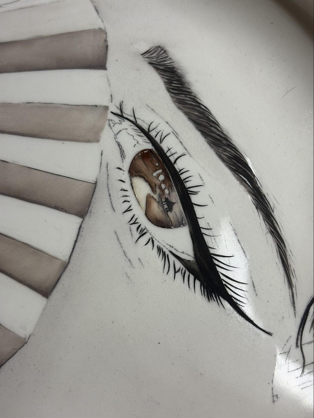 A finely painted eye in progress on a porcelain surface